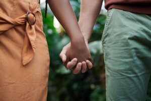 Close-up of an interracial couple holding hands in a natural outdoor setting, symbolizing love and unity.Why Foreplay Matters More Than You Think