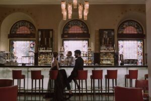Couple in elegant attire enjoying a date at a luxurious bar with a stained glass backdrop.v